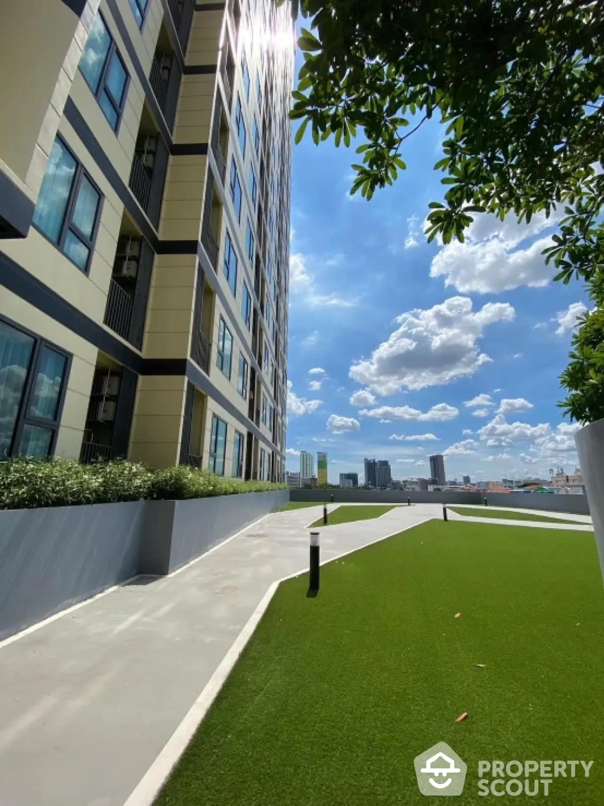 Modern high-rise building with lush green rooftop garden and stunning city view.