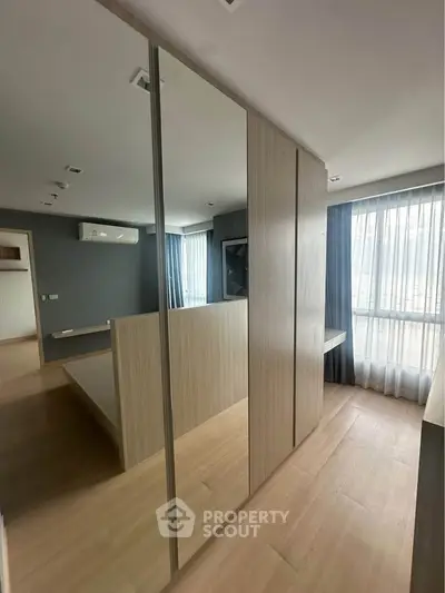 Modern bedroom with large mirrored wardrobe and natural light