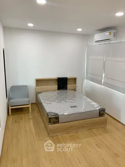 Modern bedroom with wooden flooring, air conditioning, and a stylish bed frame.