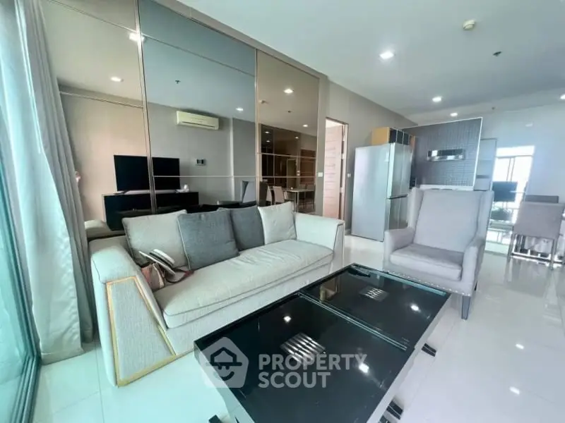 Modern living room with sleek furniture and open layout, featuring a stylish kitchen and dining area.
