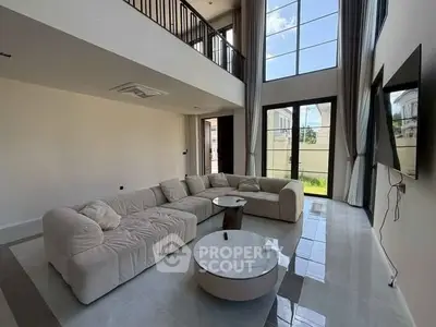 Spacious modern living room with high ceilings and large windows offering natural light.