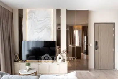 Modern living room with stylish decor and large TV, featuring elegant wall art and cozy seating area.