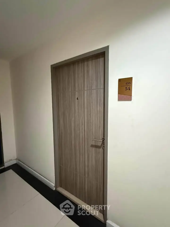 Modern apartment entrance with sleek wooden door and room number 54, showcasing contemporary design.