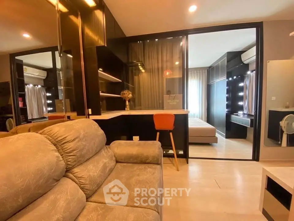 Modern living room with cozy sofa and view into stylish bedroom with mirrored closet.