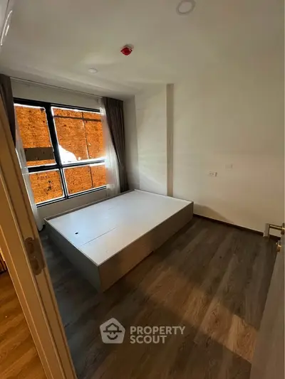 Spacious bedroom with large window and modern flooring