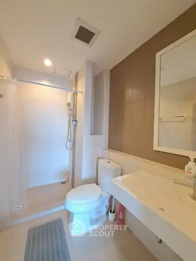 Modern bathroom with shower, toilet, and sink in a sleek design.