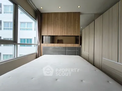 Modern bedroom with large windows and wooden accents in a high-rise apartment.
