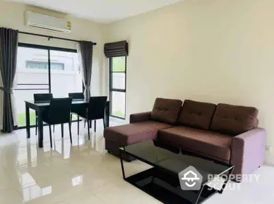 Modern living room with brown sofa and dining area, bright natural light