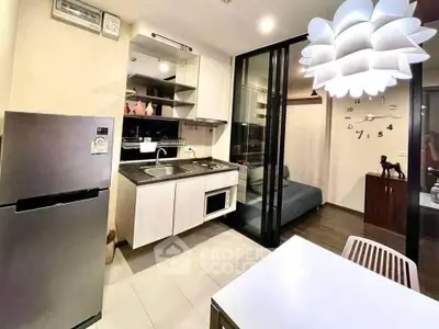 Modern kitchen with sleek appliances and stylish lighting in a cozy apartment setting.