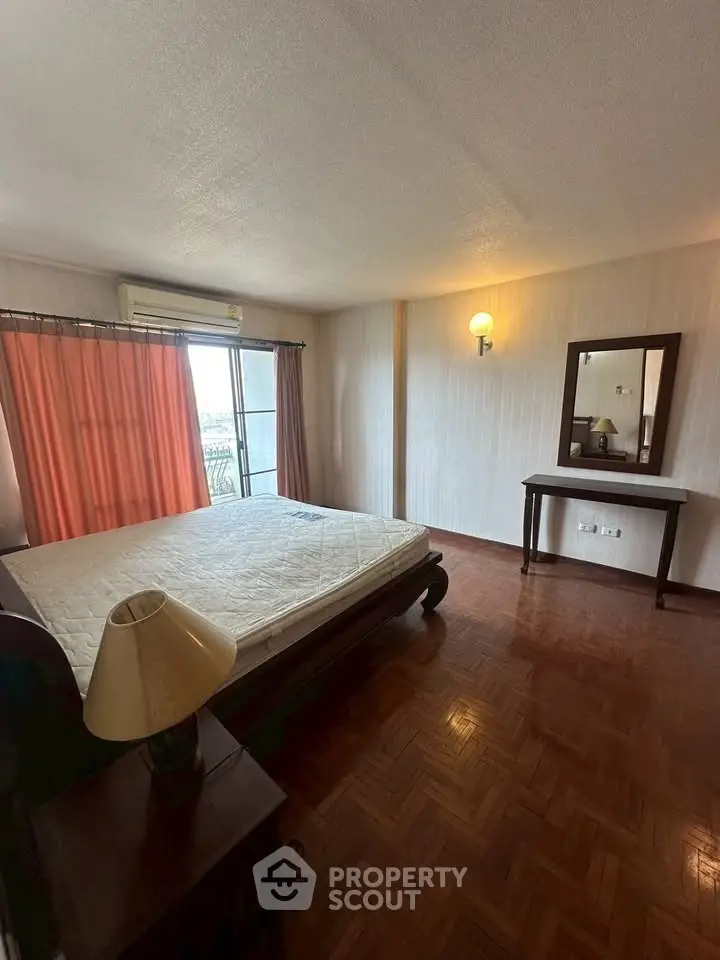 Spacious bedroom with parquet flooring and natural light