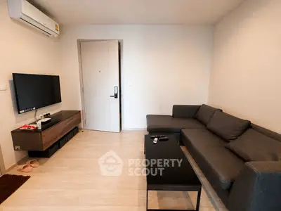 Modern living room with sleek furniture and wall-mounted TV in a cozy apartment.