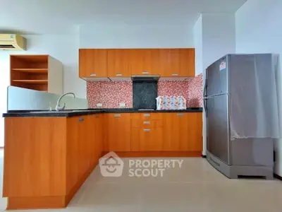 Modern kitchen with wooden cabinets and stainless steel fridge in a stylish apartment.