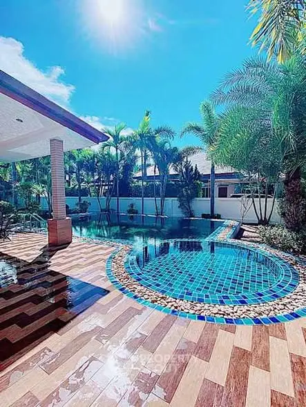 Luxurious outdoor pool area with tropical landscaping and sunny skies.