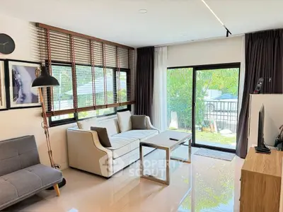 Modern living room with large windows and stylish furniture overlooking a lush garden.