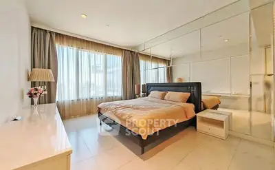 Spacious bedroom with large windows and elegant decor in a modern apartment.