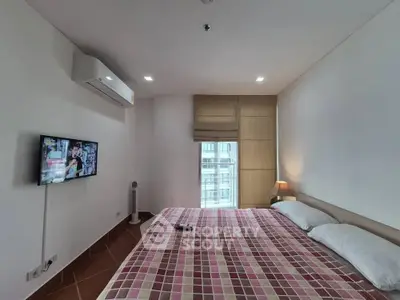 Cozy bedroom with modern air conditioning and wall-mounted TV, featuring a large window for natural light.