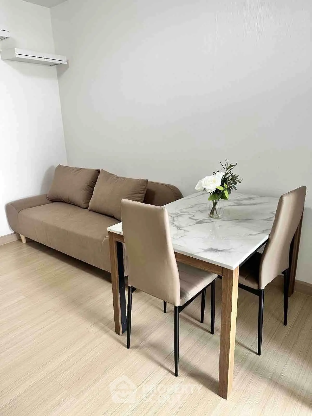 Modern living room with elegant marble dining table and cozy brown sofa, perfect for urban living.