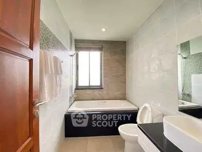 Modern bathroom with bathtub and window, featuring sleek design and neutral tones.