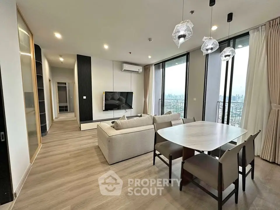 Modern living room with city view, stylish furniture, and elegant lighting in a high-rise apartment.