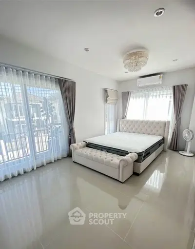 Spacious bedroom with elegant decor and large windows for natural light.