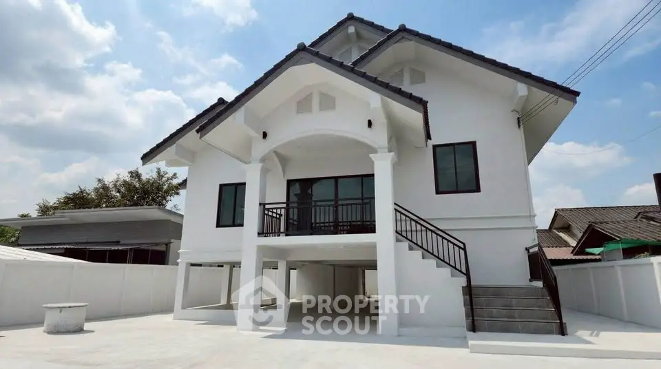 Stunning modern white house with elevated design and spacious driveway under a clear blue sky.