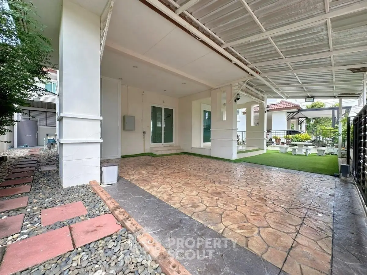 Spacious covered patio with stone flooring and lush green garden in modern home exterior.