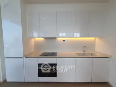 Modern kitchen with sleek white cabinetry and built-in appliances in a contemporary apartment.