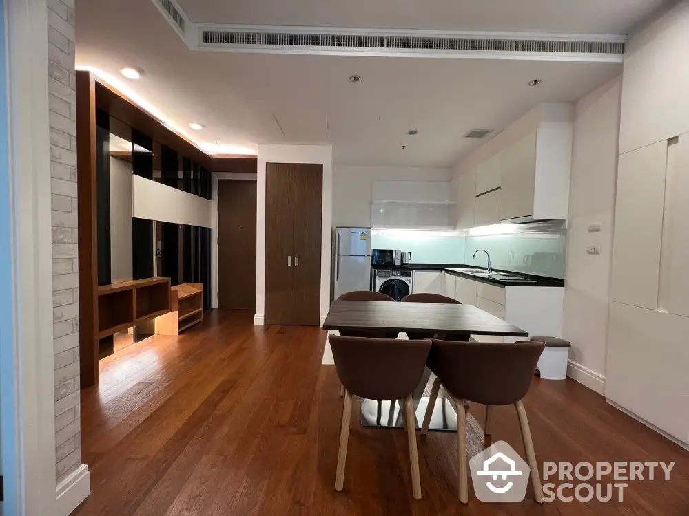 Modern open-plan kitchen and dining area with sleek appliances and wooden flooring.