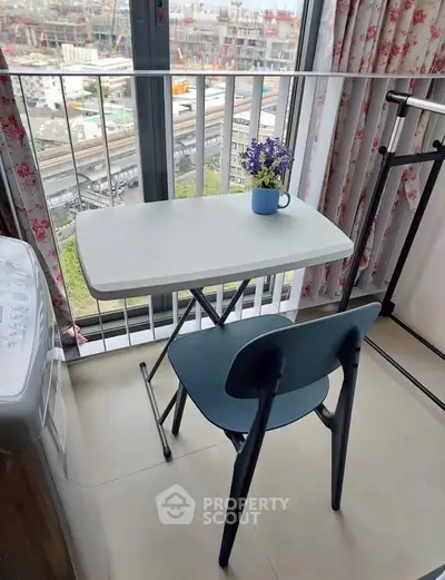 Cozy balcony with table and chair overlooking cityscape, perfect for relaxation.