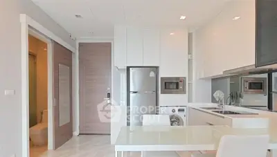 Modern kitchen with sleek appliances and integrated laundry area in a stylish apartment.