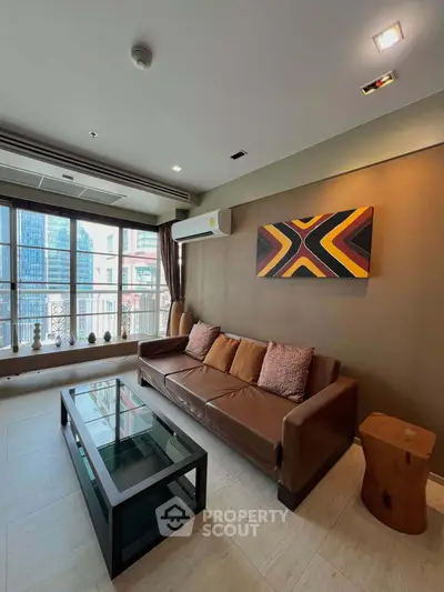 Stylish living room with modern decor and city view, featuring a leather sofa and glass coffee table.