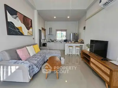 Modern living room with open kitchen, stylish decor, and cozy seating area.