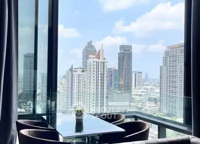 Stunning city view from modern high-rise apartment with glass dining area.