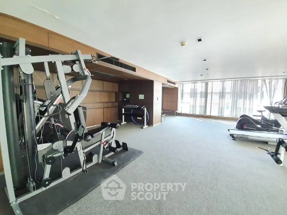 Spacious modern gym with state-of-the-art equipment and large windows for natural light.