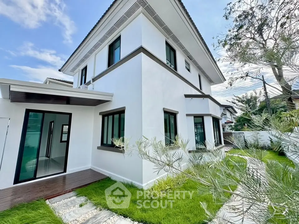 Modern two-story white house with lush green lawn and sleek design