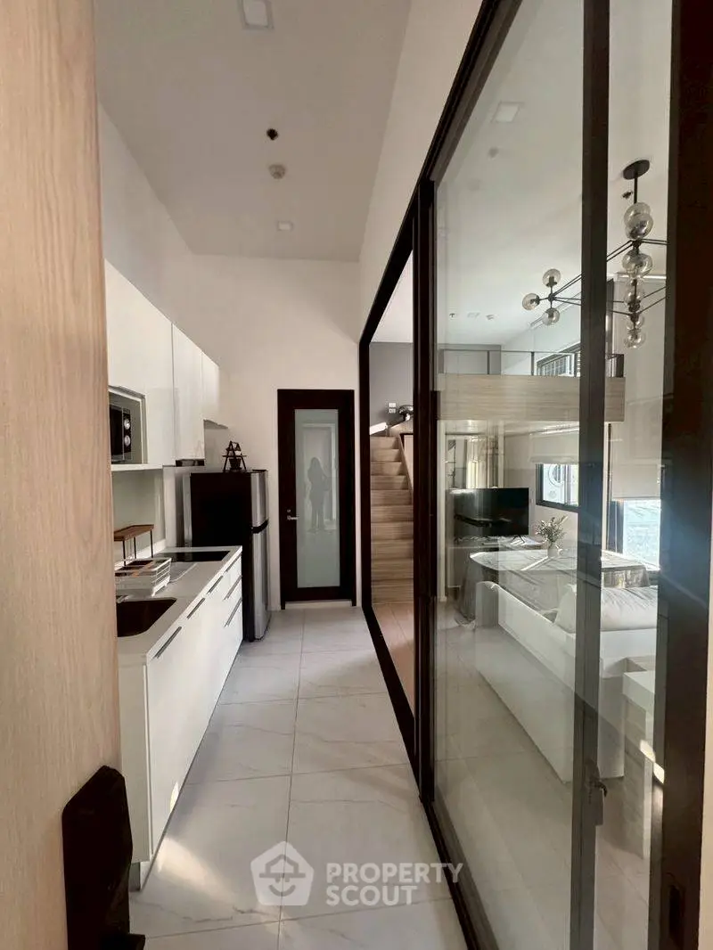 Modern kitchen with sleek design and open layout leading to a stylish living area.