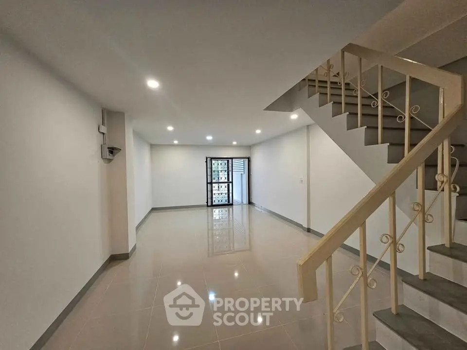 Spacious empty living room with elegant staircase and glossy tiled floor