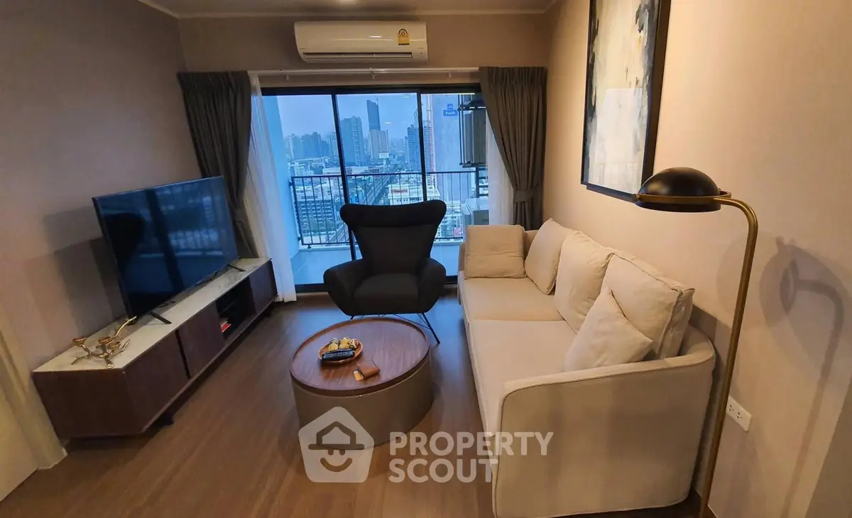 Modern living room with city view, featuring cozy sofa, stylish armchair, and large TV, perfect for urban living.