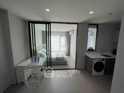 Modern studio apartment with sliding glass doors, compact kitchen, and cozy bedroom.