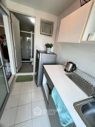 Compact kitchen with modern appliances and view into bathroom