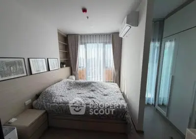 Cozy bedroom with modern decor and large window offering natural light.