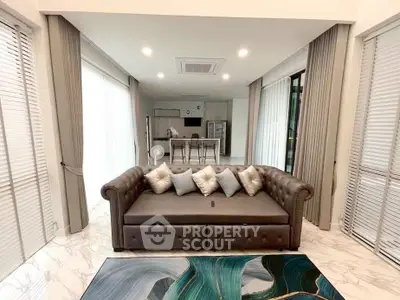 Luxurious open-plan living room with elegant sofa and modern kitchen in the background.