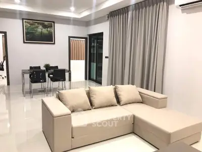 Spacious modern living room with elegant beige sofa and dining area, perfect for stylish urban living.