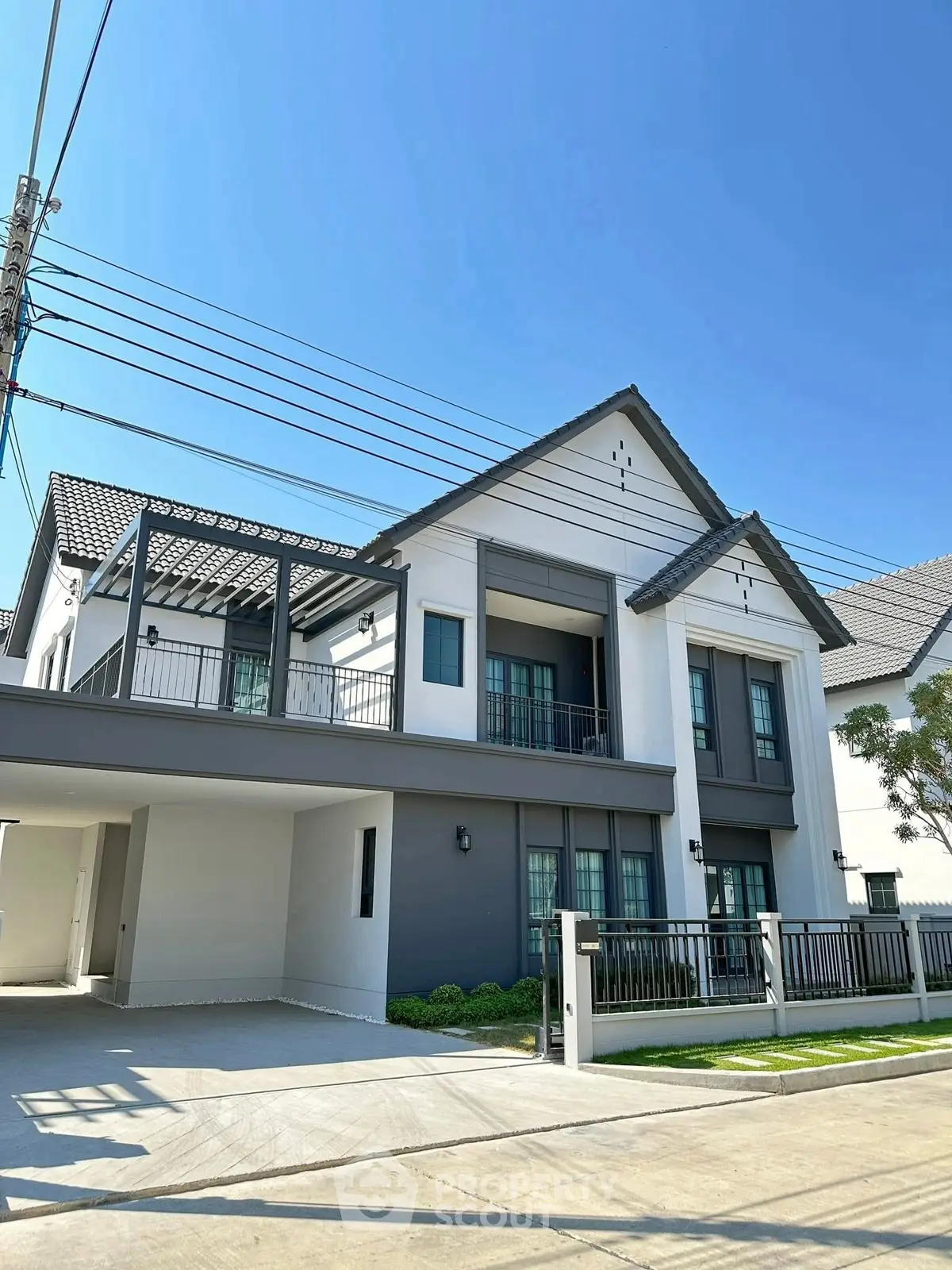 Modern two-story house with spacious driveway and elegant facade under clear blue sky.