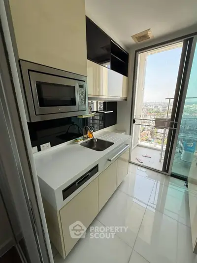 Modern kitchen with sleek cabinetry and city view from balcony.