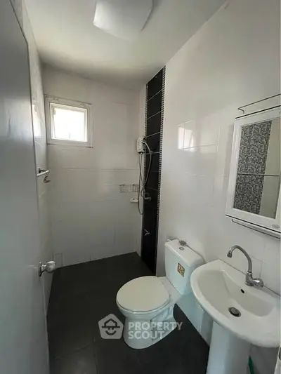 Compact bathroom with modern fixtures and natural light from window