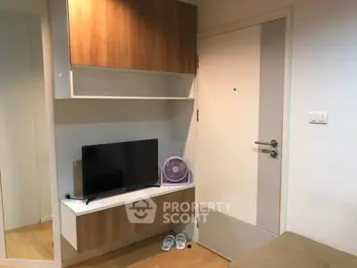 Cozy living room corner with modern TV setup and stylish wooden cabinets.