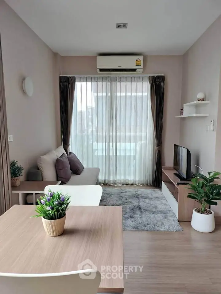 Modern living room with cozy decor and natural light, featuring a comfortable sofa and stylish TV setup.