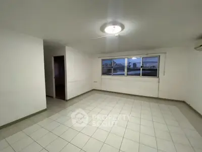 Spacious tiled living room with large window offering city views, perfect for modern living.