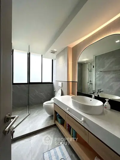 Modern bathroom with sleek design, large mirror, and glass shower enclosure.